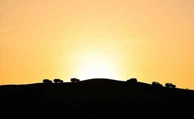 Off-road cars atop a hill at sunrise