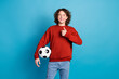 © deagreez - Photo of handsome good mood guy wear red sweater holding football ball showing thumb up isolated blue color background