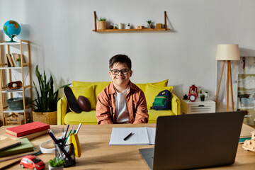 Wall Mural - A adorable boy with Down syndrome engrossed in using a laptop at his desk.