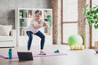 © deagreez - Full length photo of nice pensioner woman squats online training sportswear home exercising routine living room healthy lifestyle