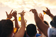 © Jacob Lund - Crowd of young people raising their hands towards the sunset in celebration at a music concert