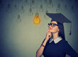 © pathdoc - thoughtful student woman with graduation hat looking up at light bulb thinking