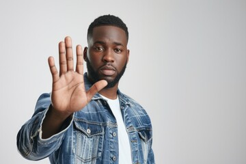 Handsome African American man showing a stop gesture with his palm outstretched to make a no or end gesture.