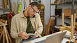 © Krakenimages.com - Handsome man counting money multitasking with a phone call in a woodworking workshop.