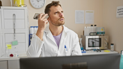 Poster - Young hispanic man with beard listens to voicemail in a hospital lab, showcasing a mix of concentration and concern.