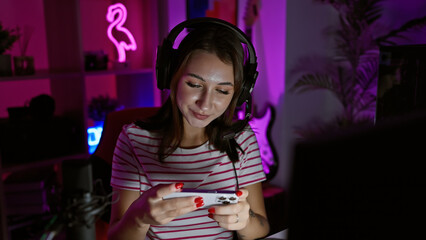 Wall Mural - A young woman with headphones enjoys gaming in a neon-lit room at night.