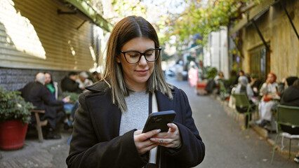 Wall Mural - Young adult woman using smartphone on a historic street in istanbul, turkey.