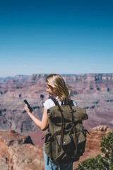 Wall Mural - young hipster girl reading message on smartphone standing on mountains viewpoint using roaming, fema
