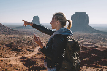 Wall Mural - smiling hipster girl pointing on scenery nature view in environment of navajo reservation holding sm