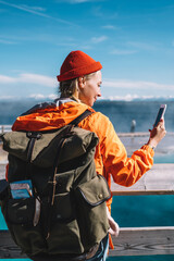 Wall Mural - smiling hipster girl with backpack checking mail on telephone during journey to famous hot springs,f