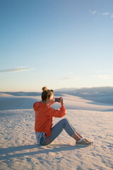 Wall Mural - young hipster girl using smartphone camera for taking picture of white dunes desert at susnet, woman