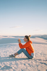 Wall Mural - female traveler making pictures of beautiful desert landscape with white dunes using telephone camer