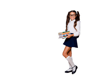 Poster - Glad positive nice smart cute small little girl with curly ponytails in white blouse shirt and blue short skirt, carrying, keeping, big book pile, copy-space. Isolated over black background