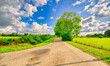 © Alex de Haas - Clouds passing over a country road in a rural landschape in The Netherlands.