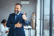 © Dragana Gordic - Cheerful businessman thumbs up posing and smiling at camera.  Portrait of happy business man looking at camera with copy space. Satisfied proud man feeling confident in a modern office.