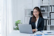 © Tj - happy young businesswoman Asian siting on the chiar cheerful demeanor raise holding coffee cup smiling looking laptop screen.Making opportunities female working successful in the office.