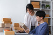 © wichayada - A happy Asian online shopping entrepreneur couple takes orders and packs products to send to customers together in their office.