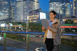 © zhouyilu - Smiling Professional Woman Using Tablet in City at Dusk