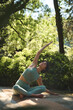 © insta_photos - Happy mindful young Hispanic woman meditating doing yoga breathing exercises feeling peace of mind, mental balance sitting in lotus pose stretching in green nature park outdoors. Vertical.