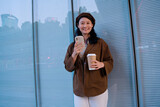 Fototapeta  - Stylish Woman Enjoying Coffee and Smartphone in City