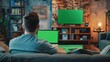 © Антон Сальников - An attractive young man works at home on a laptop computer with a green screen mock-up display. An innovative male checks social media and browses the internet from the living room of an apartment in