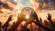 © Elena - A group of diverse hands holding up a globe against a dramatic sunset sky, symbolizing global unity and hope