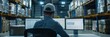© gunzexx png and bg - Back view of a man with a baseball cap working at a desk with two computer screens in a warehouse office