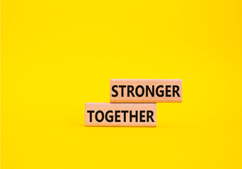 Wall Mural - Stronger together symbol. Wooden blocks with words Stronger together. Beautiful yellow background. Stronger together concept. Copy space.