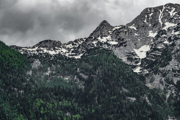 The view depicts a mountain towering over a valley, with lush greenery contrasting the rugged terrain.