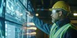 © gunzexx png and bg - Engineer in a hard hat using a futuristic digital control panel in an industrial setting