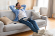 © Prostock-studio - A middle-aged man is seen relaxing on a comfortable couch, engrossed in his laptop screen. He appears calm and focused as he works or browses the internet in a cozy indoor setting.