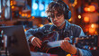 © Ekaterina - A young musician wearing headphones, playing guitar and recording in a cozy, warmly lit studio, surrounded by musical equipment