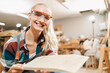 © chokniti - Attractive middle aged woman carpenter designer works with ruler, make notches on the tree in workshop. Image of modern femininity. Concept of professionally motivated women