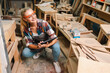 © chokniti - Attractive middle aged woman carpenter designer works with ruler, make notches on the tree in workshop. Image of modern femininity. Concept of professionally motivated women