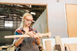 © chokniti - Attractive middle aged woman carpenter designer works with ruler, make notches on the tree in workshop. Image of modern femininity. Concept of professionally motivated women