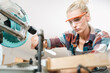 © chokniti - Attractive middle aged woman carpenter designer works with ruler, make notches on the tree in workshop. Image of modern femininity. Concept of professionally motivated women