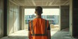© gunzexx png and bg - A construction supervisor stands with his back to the camera in an unfinished building, overseeing progress
