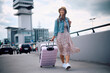 © Drazen - Happy female traveler with suitcase arriving at  airport.