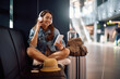 © Drazen - Happy woman using cell phone while listening music over headphones at  airport.