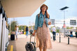 © Drazen - Young happy woman with travel bag walking at station.