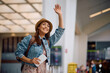 © Drazen - Happy woman waving to someone while arriving at airport.