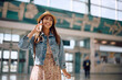 © Drazen - Happy woman talking on mobile phone at airport.