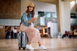 © Drazen - Happy woman text messaging on smart phone at airport.