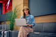 © Drazen - Smiling female tourist using laptop at airport terminal.