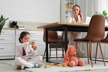 Canvas Print - Little girl playing with cubes while her mother working in kitchen