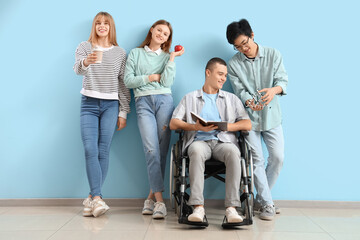 Wall Mural - Group of teenagers with boy in wheelchair near blue wall