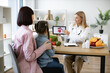 © sofiko14 - Mother with little girl at appointment with family nutritionist. Mature experienced female doctor showing tablet with gastrointestinal tract image for treatment planning to little female child.