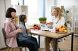 © sofiko14 - Little girl sitting on mother lap at appointment with mature female nutritionist making healthy eating plan. Beautiful female doctor holding microgreen while adding it to patients diet.