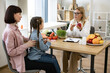© sofiko14 - Mature woman with fresh apple in hand chatting with little female child and her mother in consulting room. Experienced medical specialist giving advice on improving diet by abundance of nutrients.