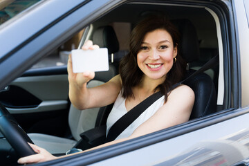 confident female driver happily displaying her driver's license in her car, radiating positivity on 